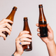 three hands holding up beer glasses